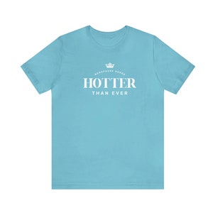May include: A light blue t-shirt with white text that reads "Menopause Queen HOTTER THAN EVER" with a crown graphic above the text.