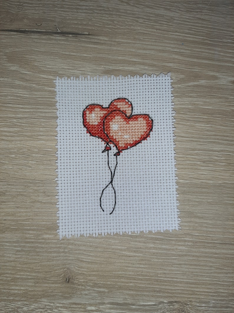 May include: Two red heart-shaped balloons tied together with black string.