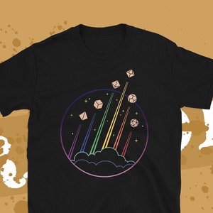 May include: Black t-shirt with a graphic of dice flying through the air on rainbow-colored beams of light. The dice are surrounded by a circle with stars and a cloud.