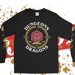 May include: Black long-sleeved t-shirt with a gold and white Dungeons & Dragons logo featuring a red 20-sided die. The logo reads "Dungeons & Dragons Est. 1974" and "Roll Initiative".