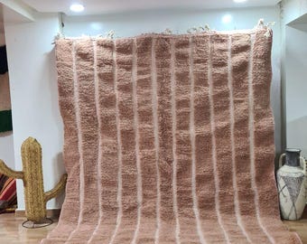 May include: A large, rectangular, pink and white striped rug with fringe on the edges. The rug is laid out on a tiled floor.