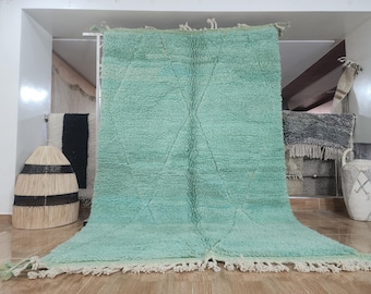 May include: A light green Moroccan rug with a diamond pattern. The rug has a fringe border and is made of wool.