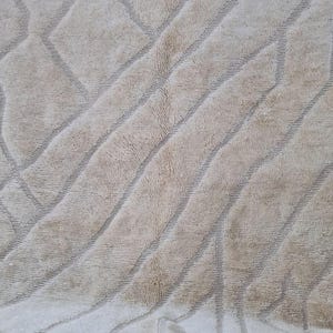K&ouml;nnte beinhalten: Beiger Teppich mit geometrischem Muster. Der Teppich hat diagonale Streifen und Rauten in einem helleren Beigeton. Der Teppich hat eine strukturierte Oberfl&auml;che und einen Fransenbesatz oben.