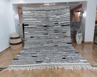 May include: A black and white striped rug with a fringe border. The rug is made of wool and has a hand-woven texture.