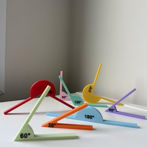 May include: A collection of multi-coloured plastic angle measuring tools in various shades including red, yellow, orange, light green, light blue, and purple. Each tool features a semi-circular base with black printed degree markings like 30, 45, 60, 90, 120, 180, and 270 degrees.