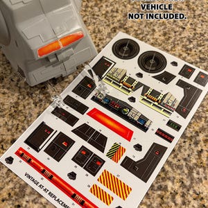 Puede incluir: Una hoja de papel blanco con calcomanías negras y rojas para un caminante AT-AT de Star Wars vintage. Las calcomanías incluyen detalles para la cabina, el motor y otras partes del vehículo. El texto en la hoja dice "PEEL-AND-STICK DECALS ONLY. VEHICLE NOT INCLUDED." y "VINTAGE AT-AT REPLACEMENT DECALS".