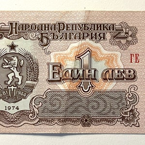 May include: A vintage 1 Bulgarian lev banknote featuring a red and brown design with a lion and wheat stalks. The text "Народна Република България" is printed in black at the top of the note. The note has a serial number "ГЕ 201211".