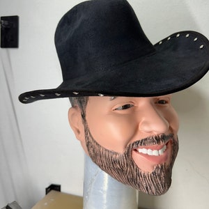 May include: A black cowboy hat with silver studs around the brim. The hat is made of suede and has a wide brim. The hat is sitting on a mannequin head with a beard.