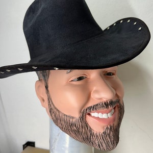 May include: A black cowboy hat with silver studs around the brim. The hat is being worn by a person with a beard and moustache.