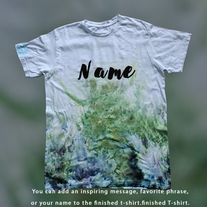 May include: A white t-shirt with a tie-dye pattern in shades of green, blue, and purple. The word "Name" is written in black on the front of the shirt.