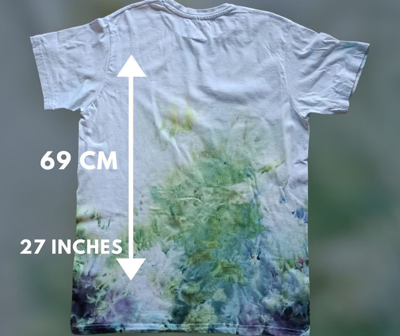 May include: White t-shirt with a tie-dye pattern in shades of green, blue, and purple. The shirt measures 27 inches in length.