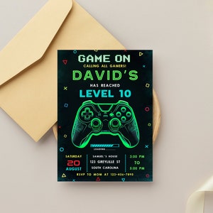 May include: A black and green birthday invitation with a neon green video game controller graphic. The text reads "Game On Calling All Gamers! David's Has Reached Level 10". The invitation includes details for a party on August 20th from 3:00 PM to 5:00 PM.