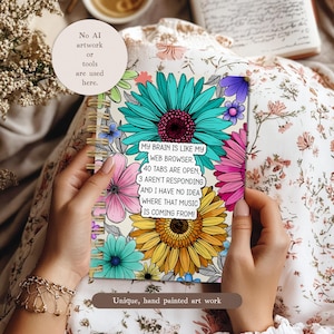 May include: A floral notebook with a spiral binding, featuring large turquoise, pink, and yellow flowers. The notebook has the text "MY BRAIN IS LIKE MY WEB BROWSER. 40 TABS ARE OPEN, 3 AREN'T RESPONDING AND I HAVE NO IDEA WHERE THAT MUSIC IS COMING FROM!"
