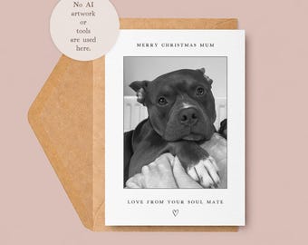 May include: A black and white greeting card featuring a dog's portrait. The text "MERRY CHRISTMAS MUM" is at the top, with "LOVE FROM YOUR SOUL MATE" and a heart symbol below. The card is inside a brown envelope.