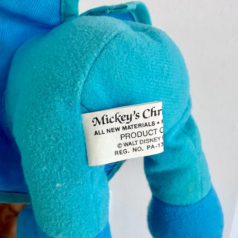 May include: A blue plush toy with a tag that reads "Mickey's Christmas. All new materials. Product of &copy; Walt Disney. Reg. No. PA-13."