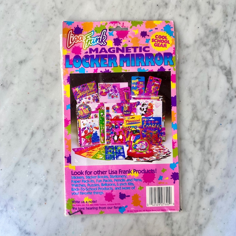 Puede incluir: Un paquete de espejo magn&eacute;tico Lisa Frank para taquillas. El paquete es rosa con salpicaduras de pintura coloridas y presenta im&aacute;genes de pegatinas, bol&iacute;grafos y otros &uacute;tiles escolares. El texto en el paquete dice "Cool School Gear".