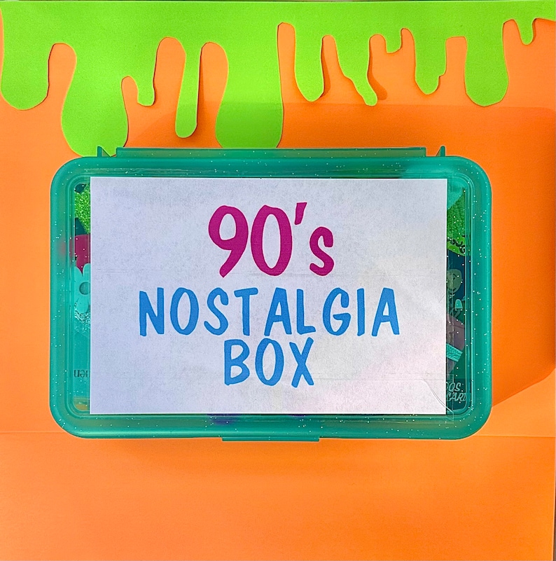 May include: A teal blue plastic box with a white label that says "90's Nostalgia Box" in pink and blue lettering. The box is sitting on an orange surface with green slime dripping down from the top.