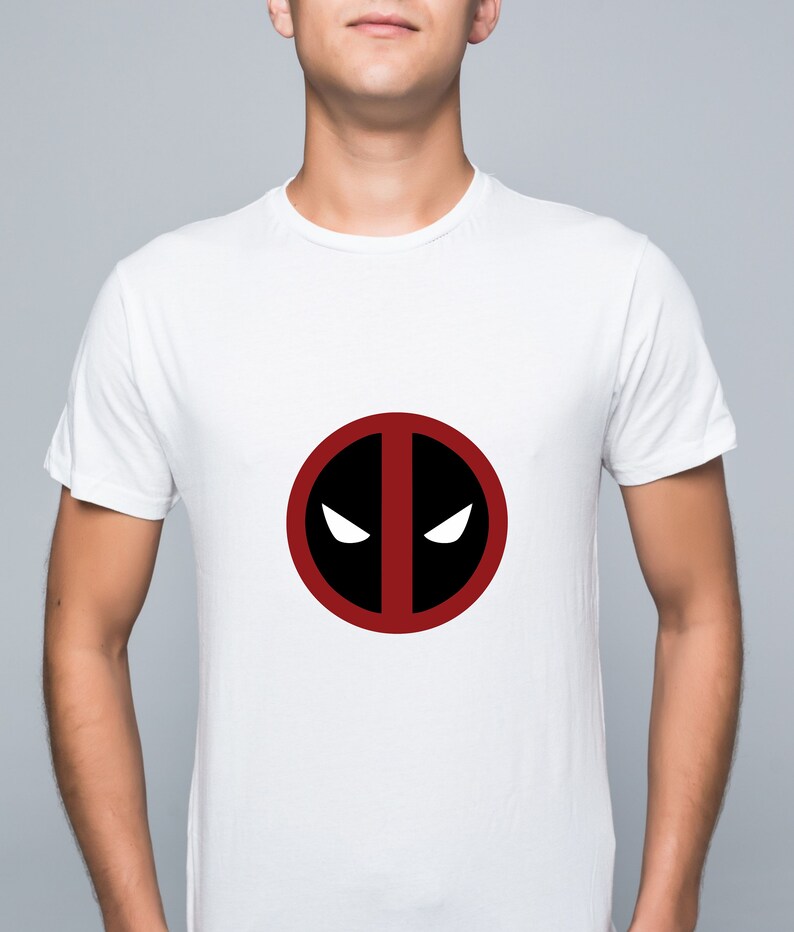 Puede incluir: Camiseta blanca con un logotipo de Deadpool rojo y negro.