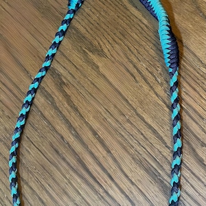 May include: A black and teal braided key chain with a silver carabiner and a silver key ring.