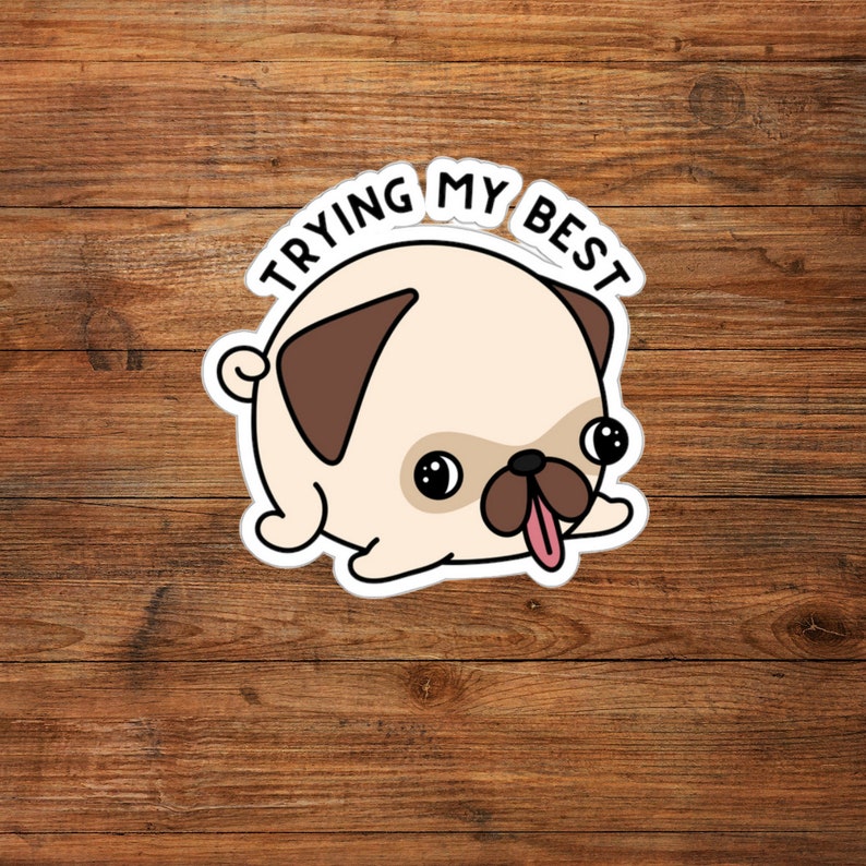 May include: A sticker featuring a cartoon pug with a light tan body, brown ears, and a pink tongue sticking out. The text "TRYING MY BEST" is arched above the pug's head in black letters. The sticker is on a wooden background.