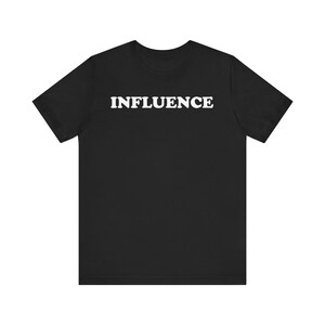 May include: Black t-shirt with the word "INFLUENCE" printed in bold, white capital letters across the chest. The shirt has short sleeves and a crew neck. The fabric appears to be a soft, comfortable material.