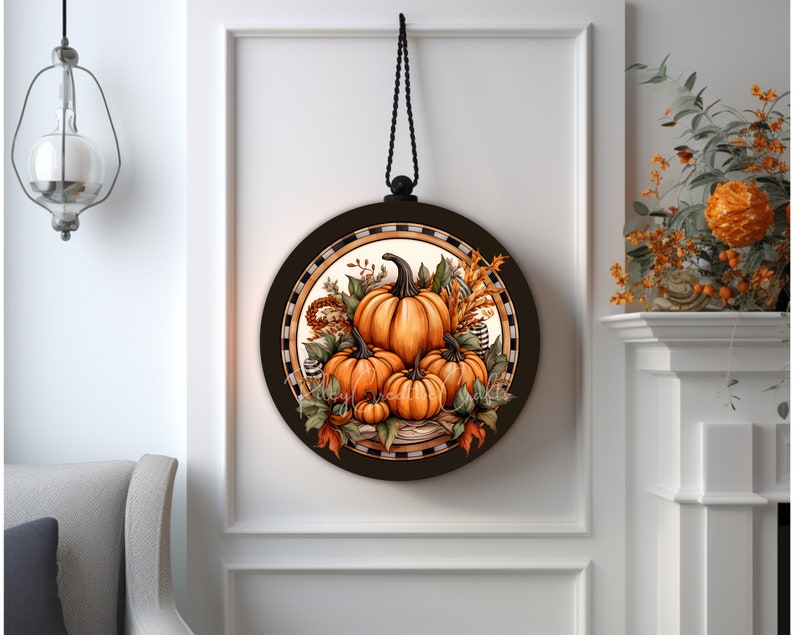 May include: A round wooden sign with a black and white checkered border. The center of the sign features a painting of orange pumpkins with fall foliage and wheat stalks. The sign is hanging from a black cord.