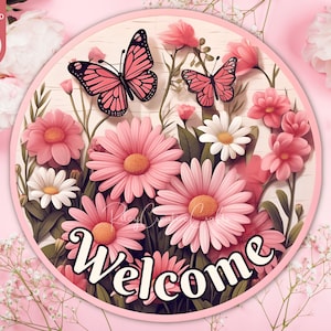 May include: A round pink welcome sign with a floral design. The sign features pink and white flowers, butterflies, and the word "Welcome" in a white script font.