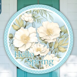 May include: A round, blue and white polka dot door hanger with a floral design and the text "Hello Spring".
