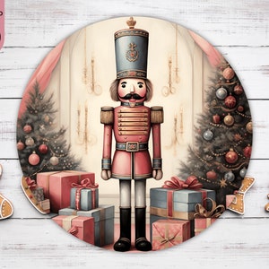 Peut inclure: Une illustration ronde d'un casse-noisette de Noël traditionnel debout devant un sapin de Noël décoré avec des cadeaux en dessous. Le casse-noisette porte un uniforme rouge et or avec un chapeau bleu et une plume blanche. L'arrière-plan est de couleur crème clair avec un rideau rose.