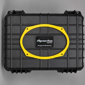 May include: A black rectangular protective hard case with a grid-patterned exterior. Centered on the lid is a black rectangular badge with the white text Apache 3800 Rugged Mobility. A yellow oval frame is positioned over the center of the lid.