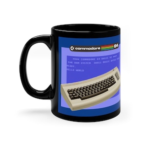 Könnte beinhalten: Schwarze Kaffeetasse mit einem blauen und weißen Bild eines Commodore 64 Computers mit dem Text "commodore 64" und "READY. HELLO WORLD" auf der Tasse.