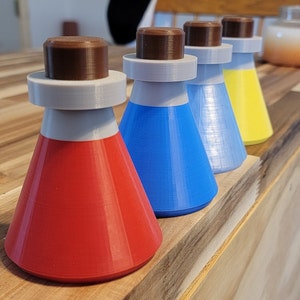 May include: Four small glass bottles with cork stoppers. The bottles are red, blue, silver, and yellow.