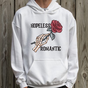 May include: White hoodie with a skeleton hand holding a red rose and the text "HOPELESS ROMANTIC".