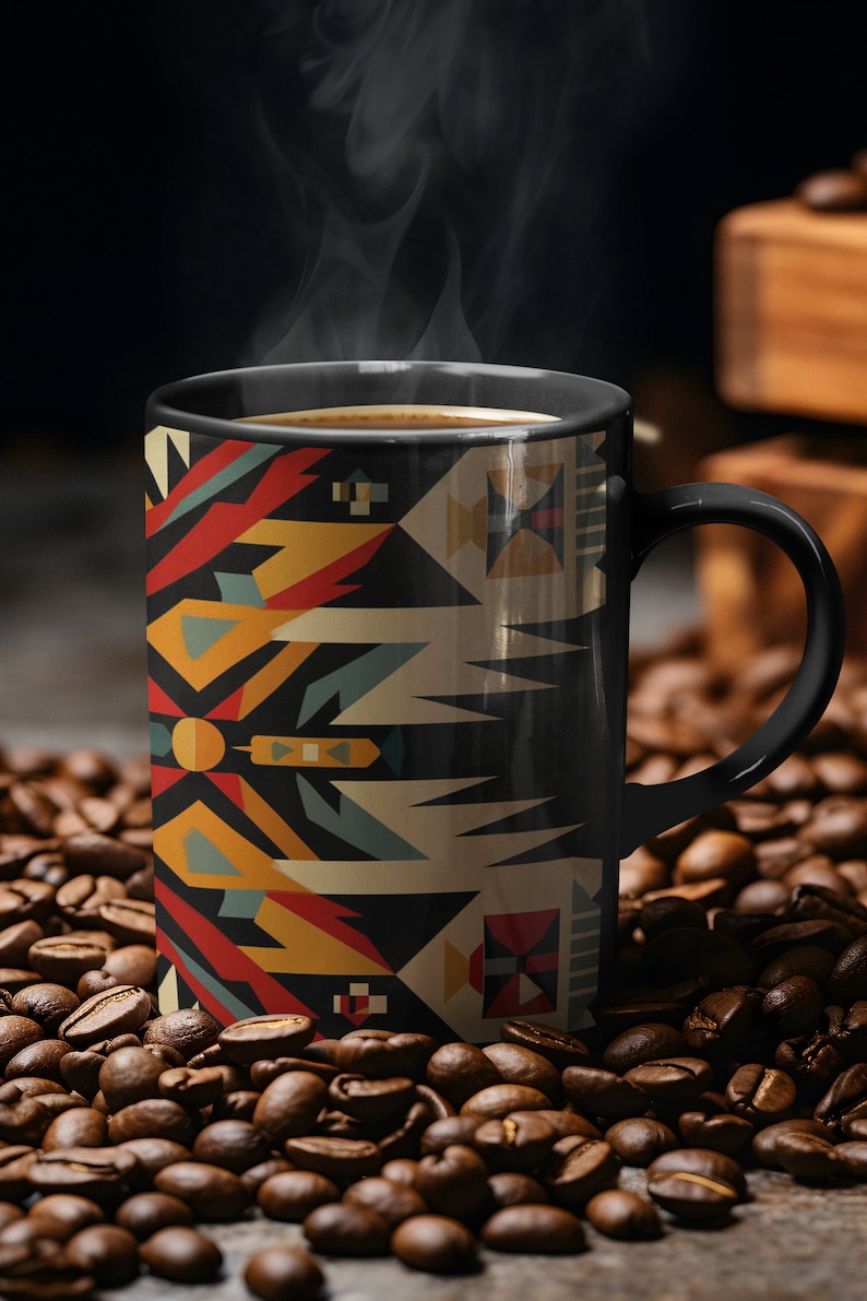 May include: A black coffee mug with a geometric pattern in shades of red, yellow, blue, and white. The mug is filled with coffee and steam is rising from the top. The mug is sitting on a bed of coffee beans.