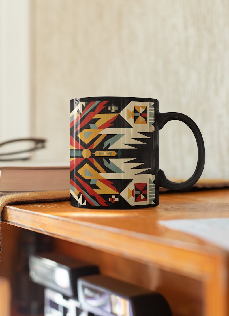 May include: Black ceramic mug with a geometric pattern in red, yellow, blue, and white. The pattern is reminiscent of Native American art.