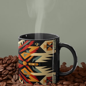 May include: A black coffee mug with a geometric pattern in shades of red, orange, yellow, blue, and white. The mug is sitting on a bed of coffee beans.