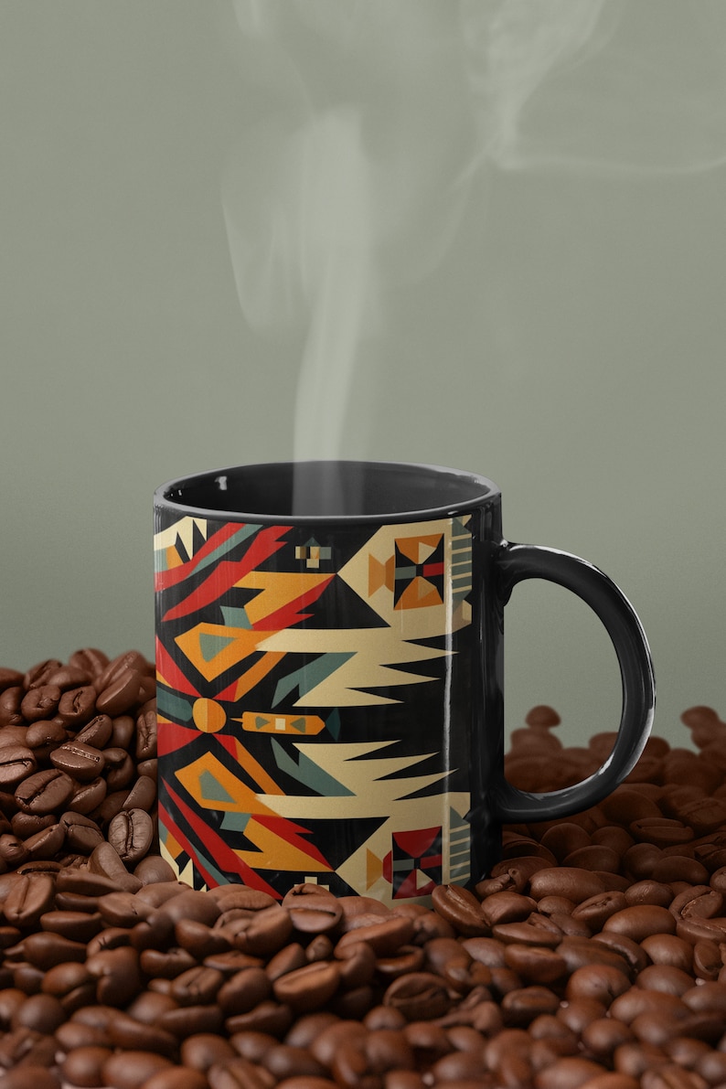 May include: A black coffee mug with a geometric pattern in shades of red, orange, yellow, blue, and white. The mug is sitting on a bed of coffee beans.