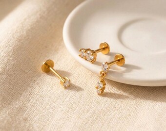 Set met drie piercings, 3 kleine gouden kraakbeenpiercings, een platte piercing met hanger, een zilveren tragus-, helix- en conch-oorbel, en een set met marquise-stenen.