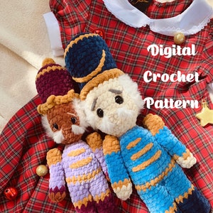May include: Two crocheted nutcracker dolls in blue, purple, and brown with white faces and black eyes. The dolls are sitting on a red and black checked fabric with the text "Digital Crochet Pattern" in white.