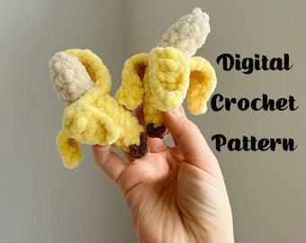 Puede incluir: Un juguete de peluche de plátano tejido a crochet en amarillo y marrón. El juguete se sostiene en una mano. El texto "Digital Crochet Pattern" está escrito en negro sobre un fondo blanco.