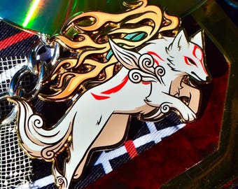 May include: A white wolf enamel pin featuring red markings and flowing orange flames along its back. The wolf is depicted in a dynamic leaping pose with stylised cloud patterns on its shoulder. The pin is attached to a silver metal chain link.