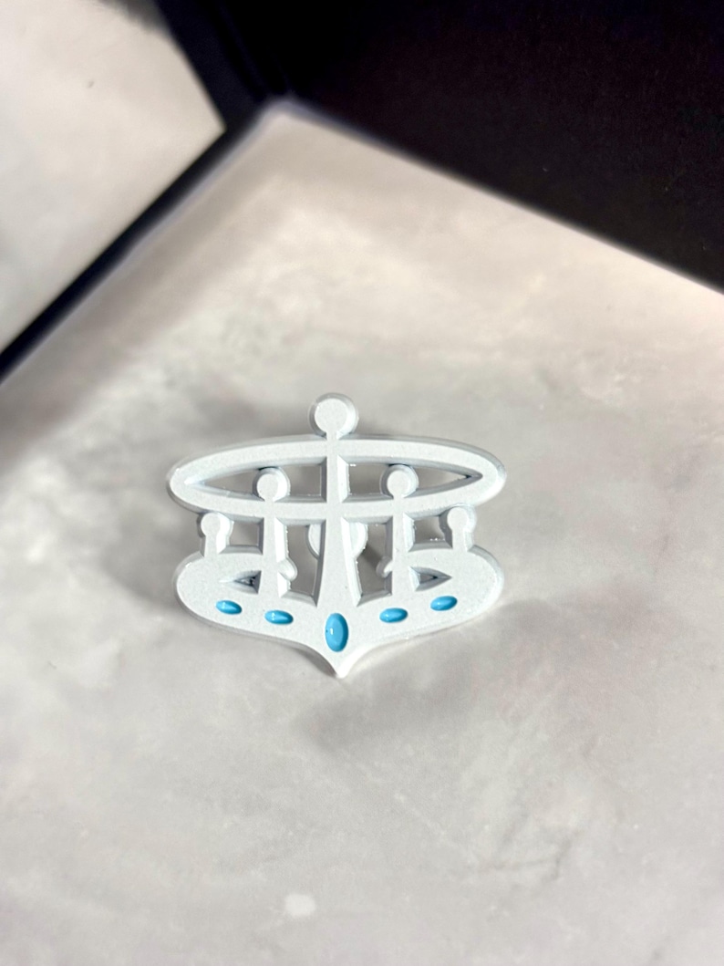 May include: White metal crown with a blue gem in the center and five smaller blue gems around the base.