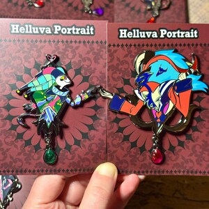 Peut inclure: &Eacute;pingles en &eacute;mail repr&eacute;sentant des personnages de "Helluva Boss". Les &eacute;pingles pr&eacute;sentent des motifs d&eacute;taill&eacute;s aux couleurs vives, notamment le bleu, le rouge, le vert et l'or. Chaque &eacute;pingle a un charme d&eacute;coratif. Les cartes indiquent "Helluva Portrait."