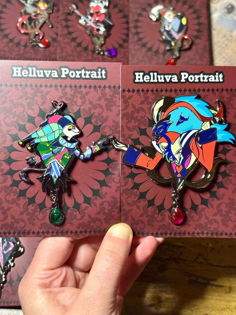 Peut inclure: &Eacute;pingles en &eacute;mail repr&eacute;sentant des personnages de "Helluva Boss". Les &eacute;pingles pr&eacute;sentent des motifs d&eacute;taill&eacute;s aux couleurs vives, notamment le bleu, le rouge, le vert et l'or. Chaque &eacute;pingle a un charme d&eacute;coratif. Les cartes indiquent "Helluva Portrait."