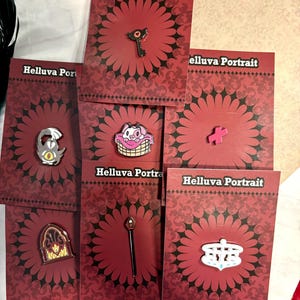 May include: Set of 7 Helluva Boss enamel pins featuring characters and objects from the show. The pins are on red cards with a black floral pattern and the text "Helluva Portrait".