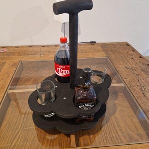 Könnte beinhalten: Ein schwarzer Getränkehalter aus Holz mit Griff, der eine Flasche Soda, eine Flasche Jack Daniel's und zwei Schnapsgläser hält. Der Halter steht auf einem Holztisch mit Glasplatte.