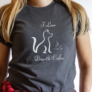 May include: A dark grey t-shirt with a white graphic of a dog and a coffee cup. The text on the shirt reads "I Love Dogs & Coffee".