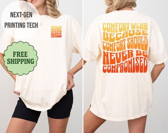 Puede incluir: Camiseta color crema con el texto "COMFORT WEAR BECAUSE COMFORT SHOULD NEVER BE COMPROMISED" en naranja y amarillo. La parte delantera de la camiseta tiene una versión más pequeña del texto. La camiseta es de corte holgado.