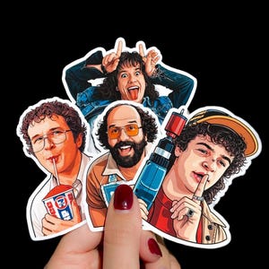 Peut inclure: Ensemble de quatre autocollants représentant des personnages de dessins animés. L'un montre une personne avec la langue tirée et les doigts en l'air. Un autre montre une personne buvant dans une tasse. Le troisième montre une personne tenant une perceuse.