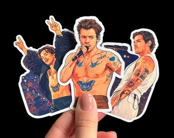 Op de afbeelding: Een verzameling van drie stickers met illustraties van een zanger. De zanger wordt shirtless afgebeeld met tatoeages, waaronder een vlinder en het woord "Fine Line". Eén sticker toont de zanger met een microfoon.